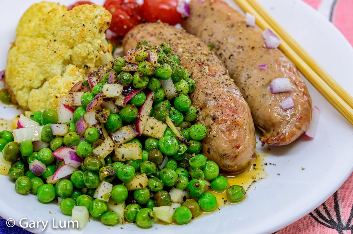 Close up. Oven-baked pork sausages, cauliflower, peas, and cherry tomatoes. Gary Lum.
