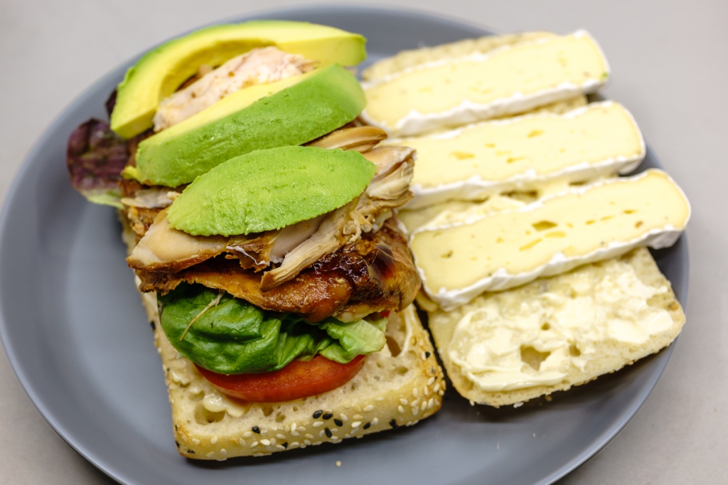 Gochujang chicken on Turkish bread with mayonnaise, tomato, lettuce, avocado, and brie